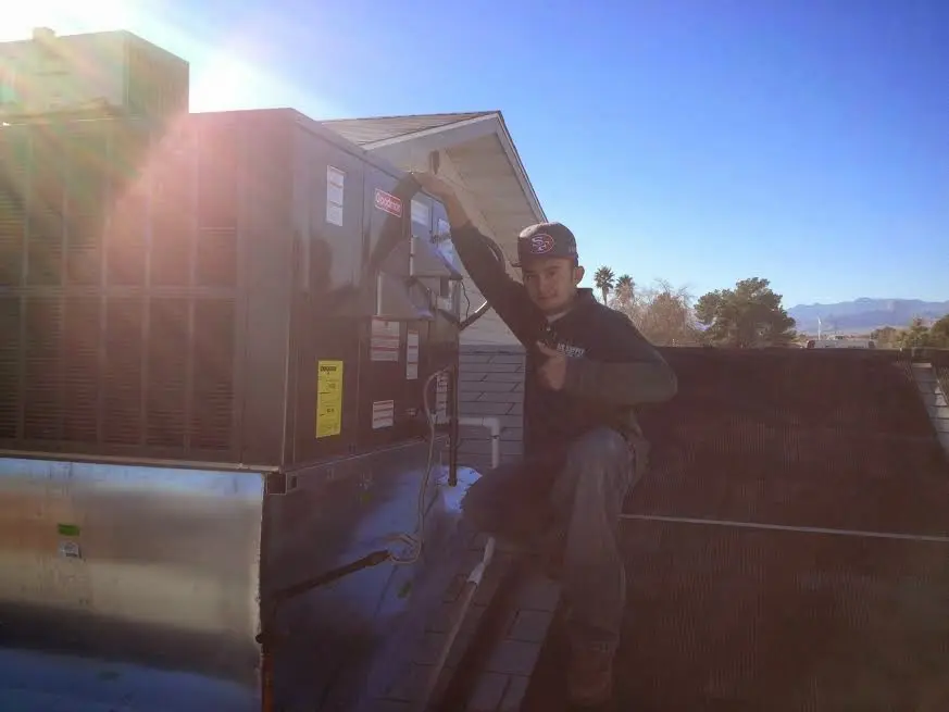 HVAC technician performing Air Duct Cleaning on a rooftop unit in Tucson Estates