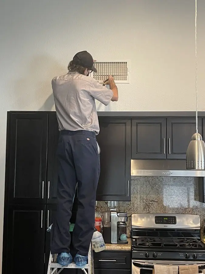 Technician inspecting an air vent during HVAC service in Tucson Estates